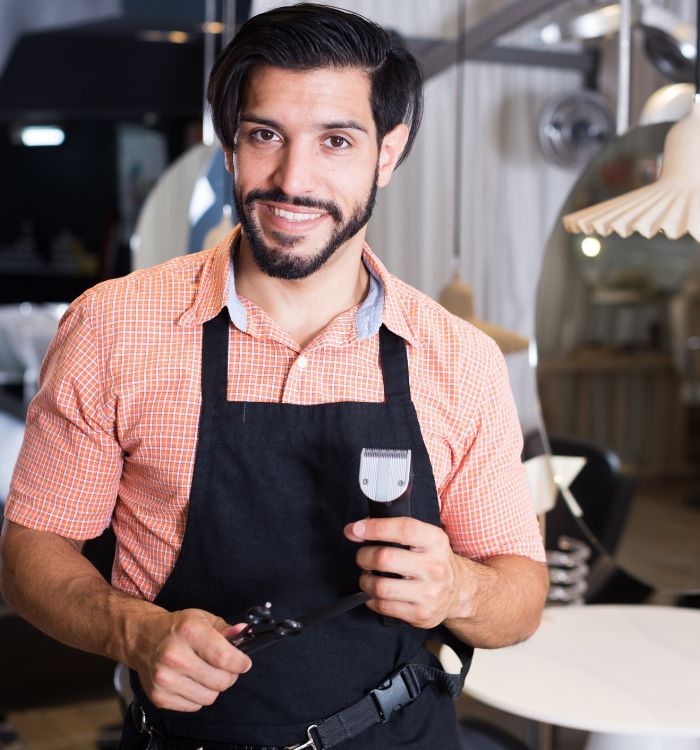 A man wearing a black apron and orange shirt.