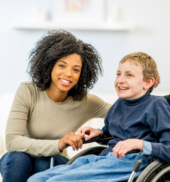 A woman and a boy sitting in a wheelchair.