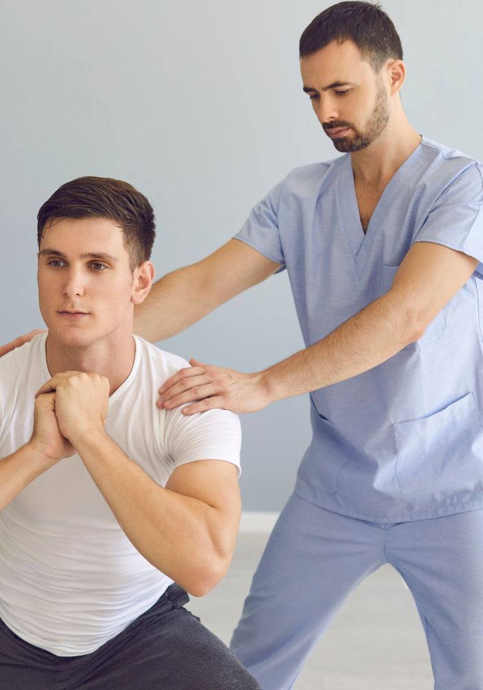 A man in a white shirt is getting assistance from a man in a blue shirt.