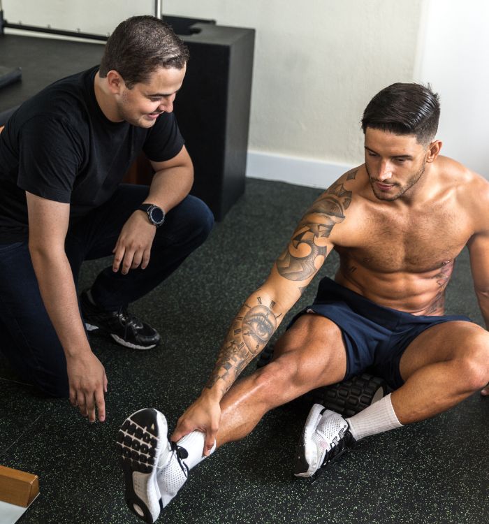A man with a tattoo is getting his foot stretched.