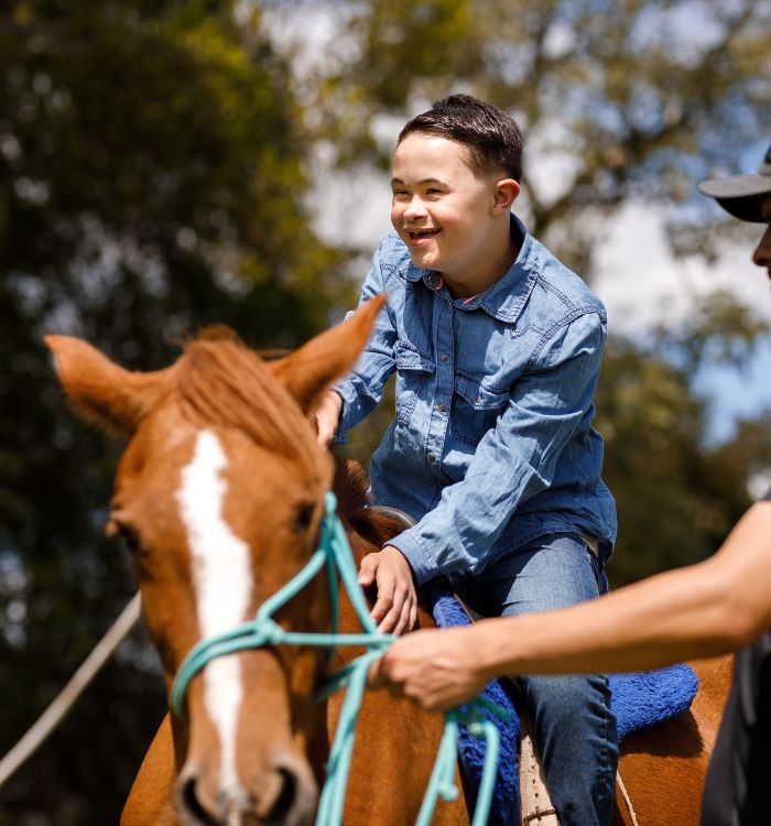 A young boy riding a horse with a green rope around its head.