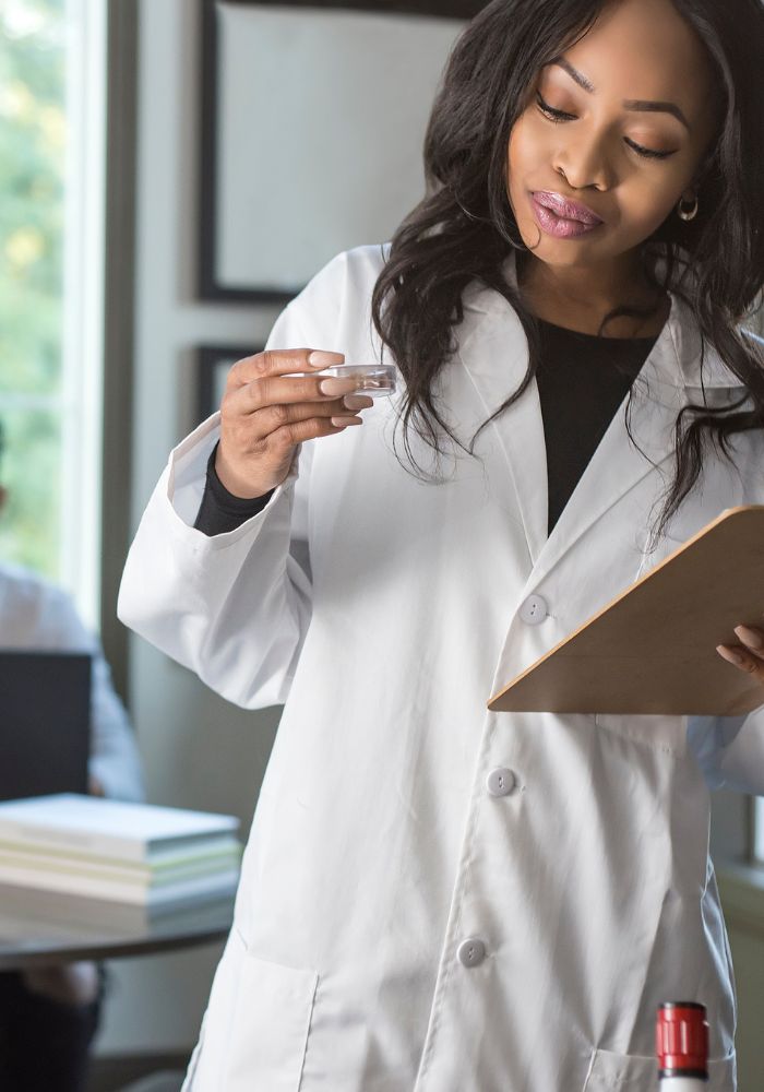 A woman in a white lab coat holding a test tube.