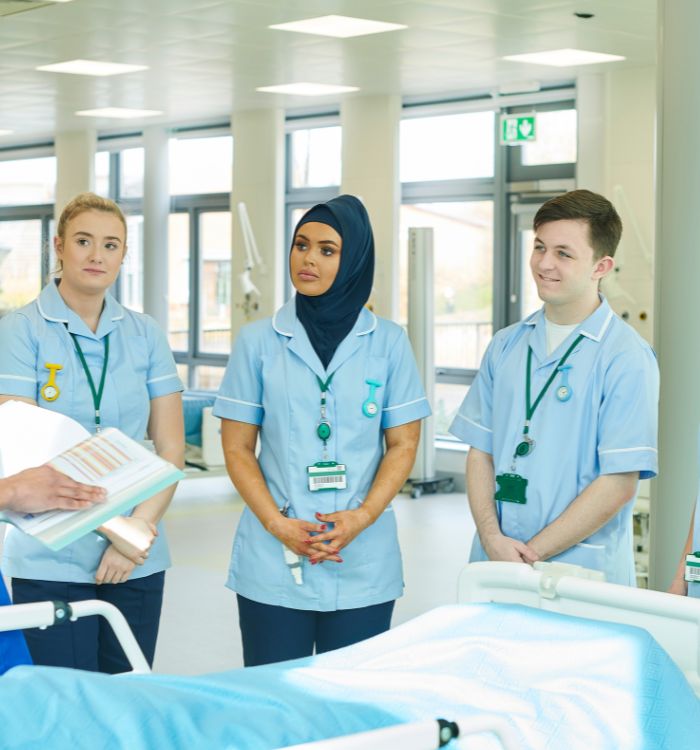 A group of nurses standing in front of a hospital bed.