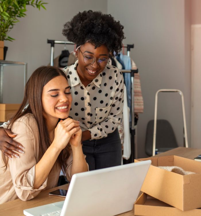 Two women standing in front of a laptop.