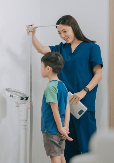A woman holding a measuring tape next to a boy.