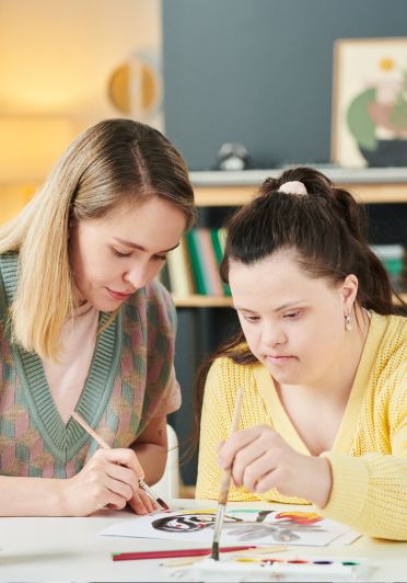 A woman and girl are painting a picture.