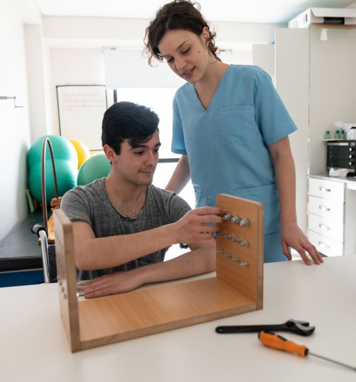 A man and woman engaged in the assembly of a wooden box, surrounded by tools and wood pieces in a workshop setting.