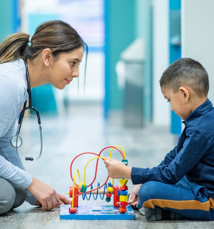 A woman and a child joyfully playing together with colorful toys on a soft carpet.