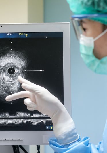 A woman with a surgical mask is directing attention to a computer screen, possibly discussing its contents or findings.