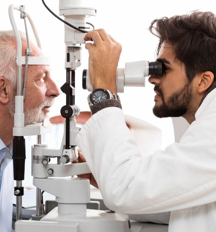 An optometrist examines an elderly man's eyes during a routine eye check-up