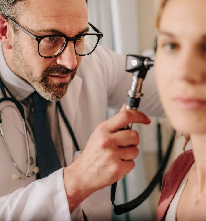 A physician inspects a woman's ear.