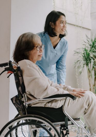 A woman in a wheelchair converses with another woman staning beside the wheelchair.