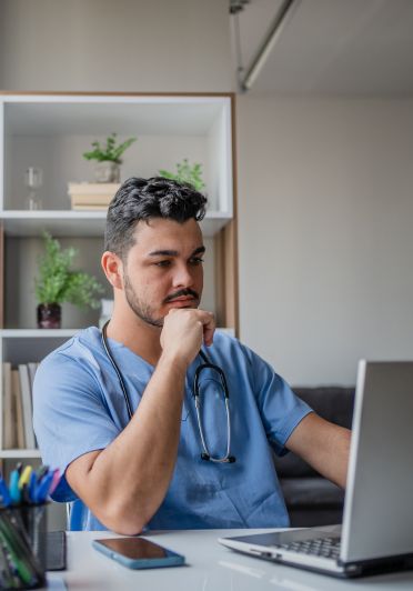 A male doctor working at a desk with a laptop.