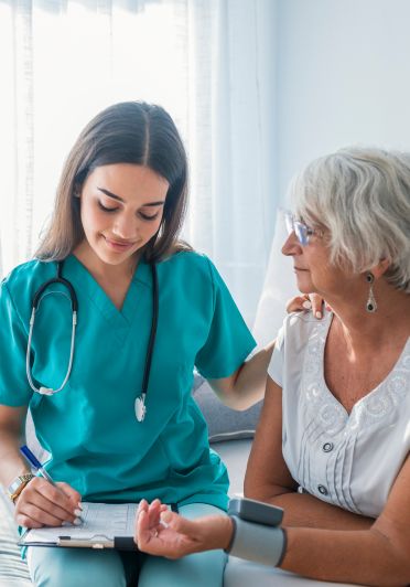  A nurse converses with an elderly woman, providing care and support.
