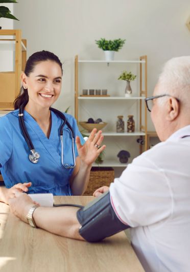 A nurse converses with an elderly man, providing care and support.