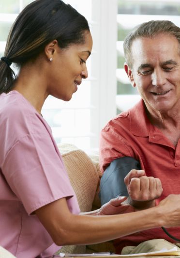 A nurse is taking the blood pressure of an older man.