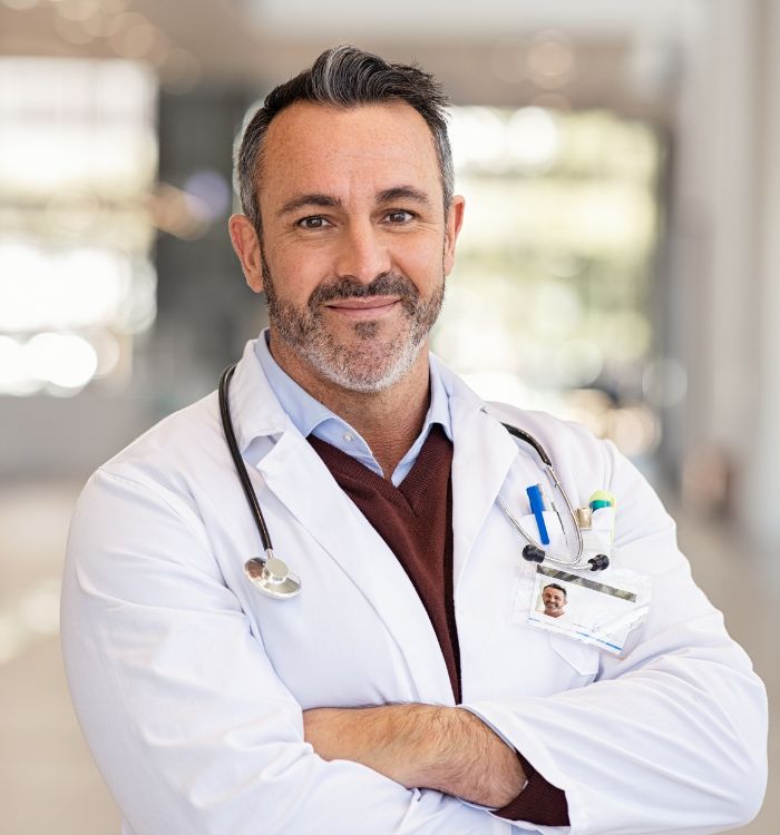  A male doctor in a white coat stands in a hospital hallway.
