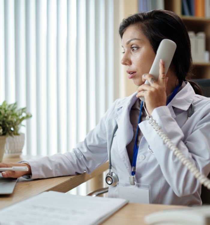 A woman in a doctor's coat is speaking on the phone