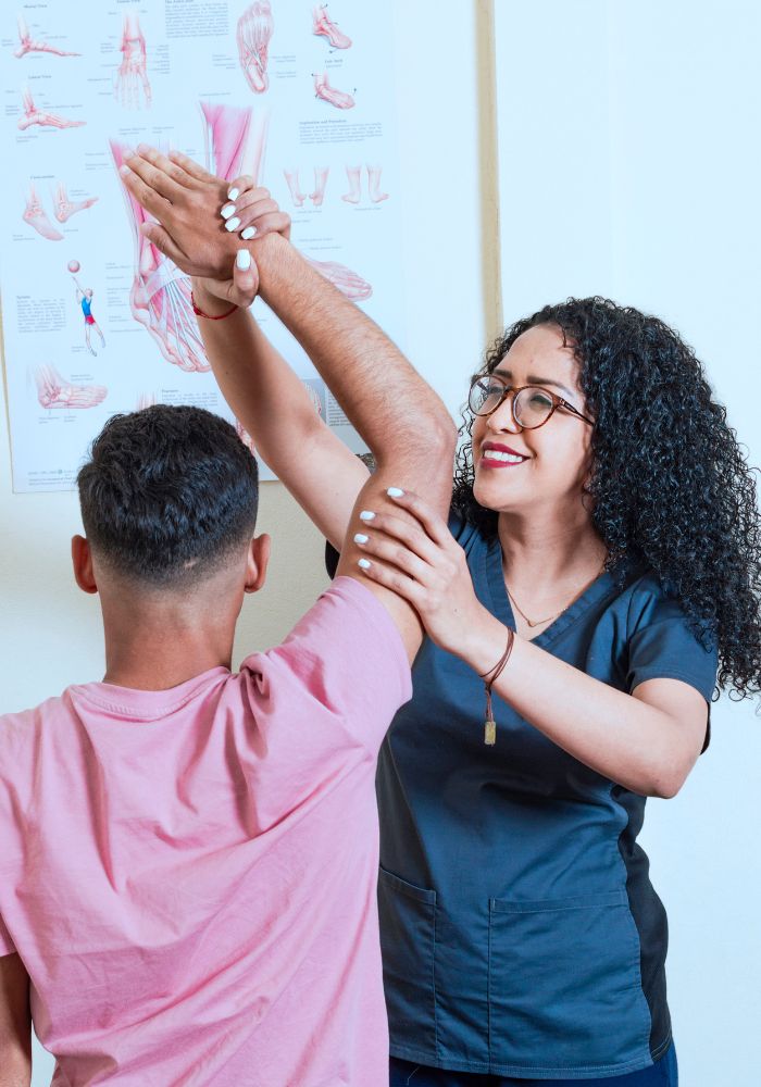 
A woman is aiding a man by holding his arm, showcasing a supportive interaction between them.
