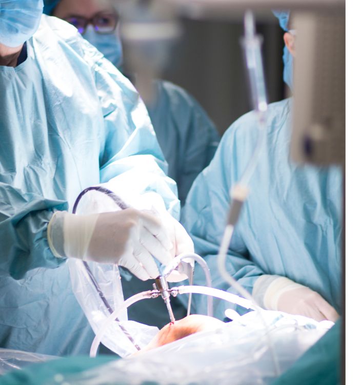 A surgeon in scrubs performs an operation on a patient lying on the operating table.