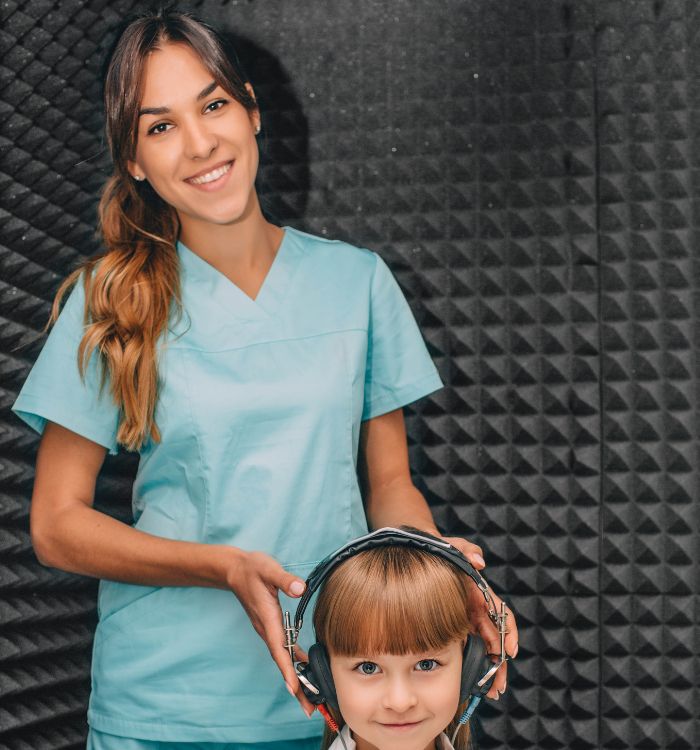 A woman in a blue shirt and headphones is holding a child's head.