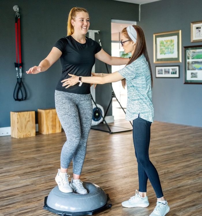 Two women are standing on a balance board.