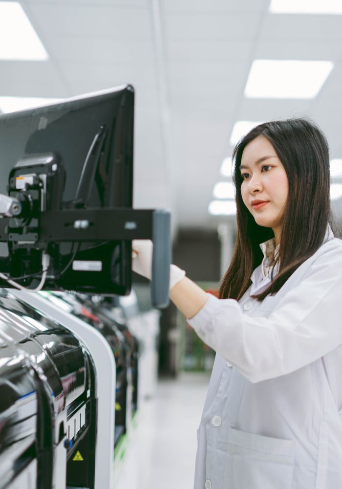 A woman in a white lab coat is working on a computer.