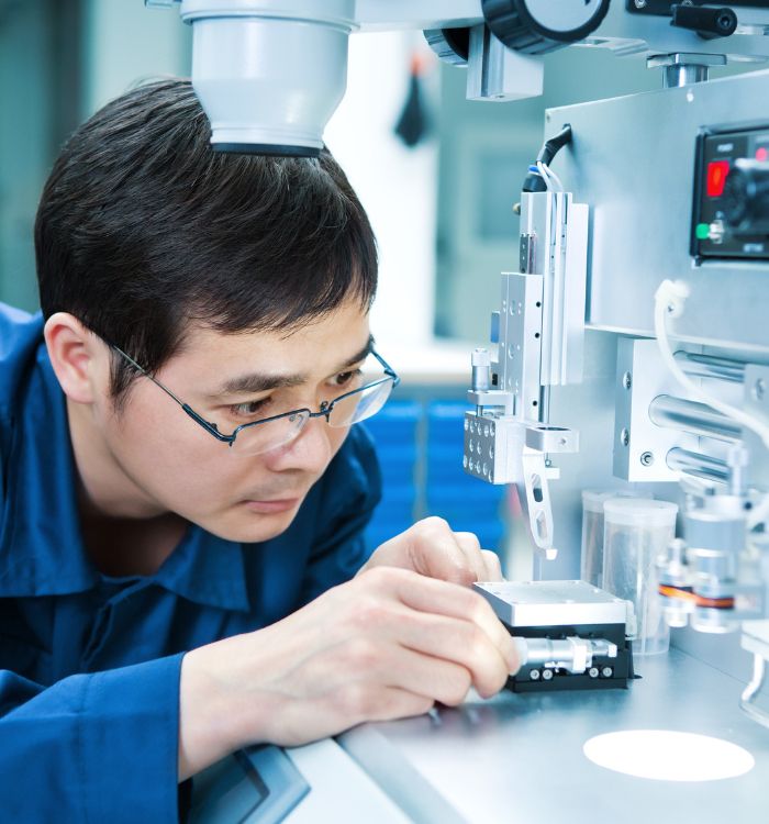A man wearing glasses and a blue shirt is working on a machine.