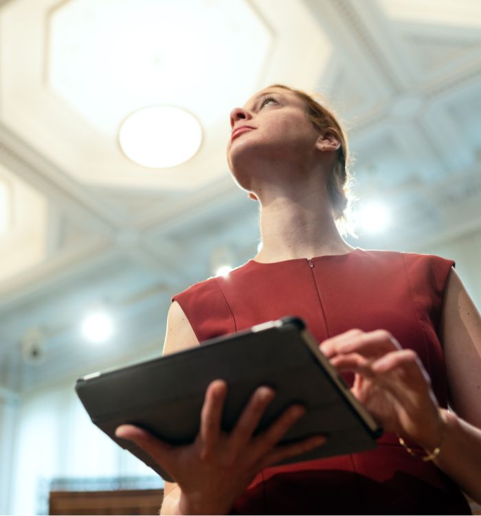 A woman in a red dress holding a tablet.
