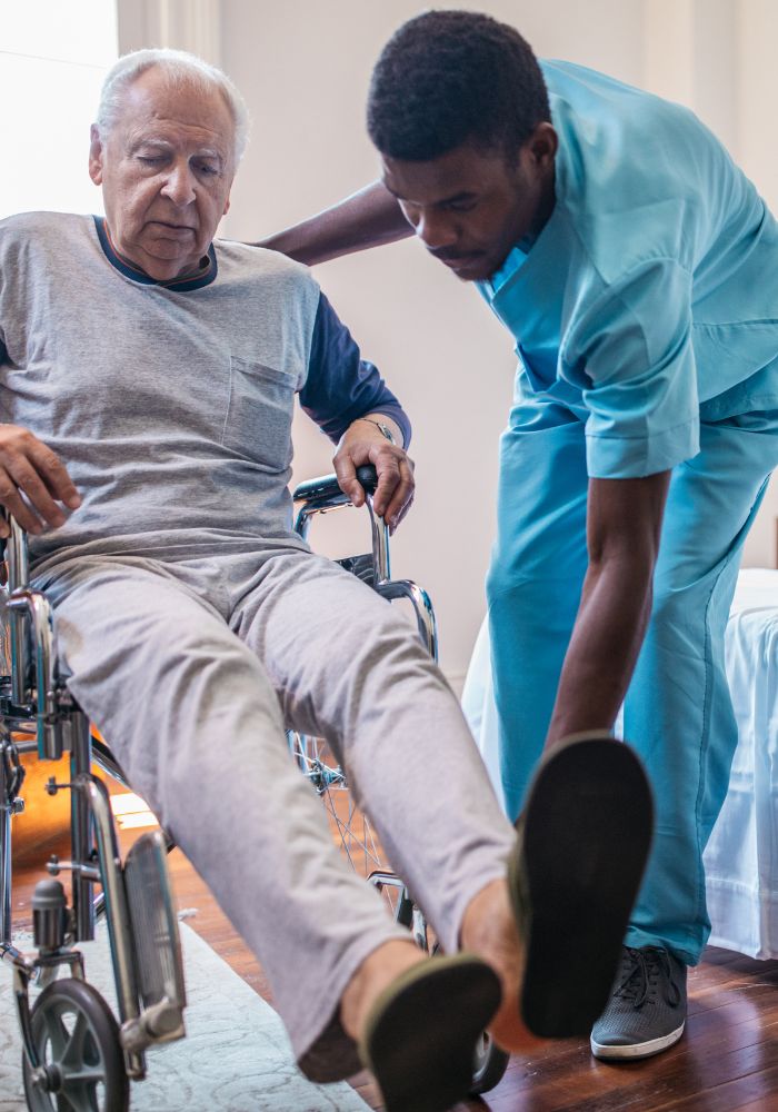 A man in a wheelchair with a nurse attending to him.