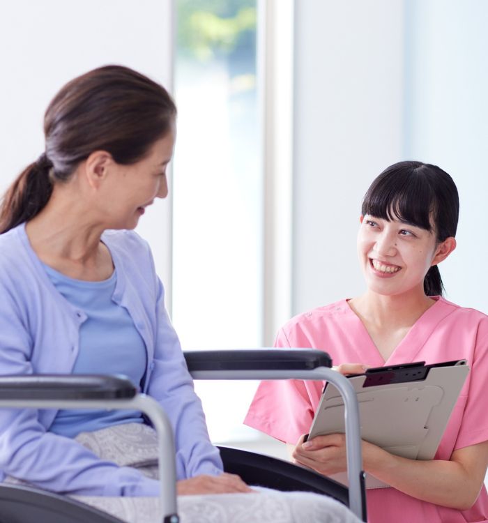 A woman in a pink shirt is smiling at a woman in a blue shirt.