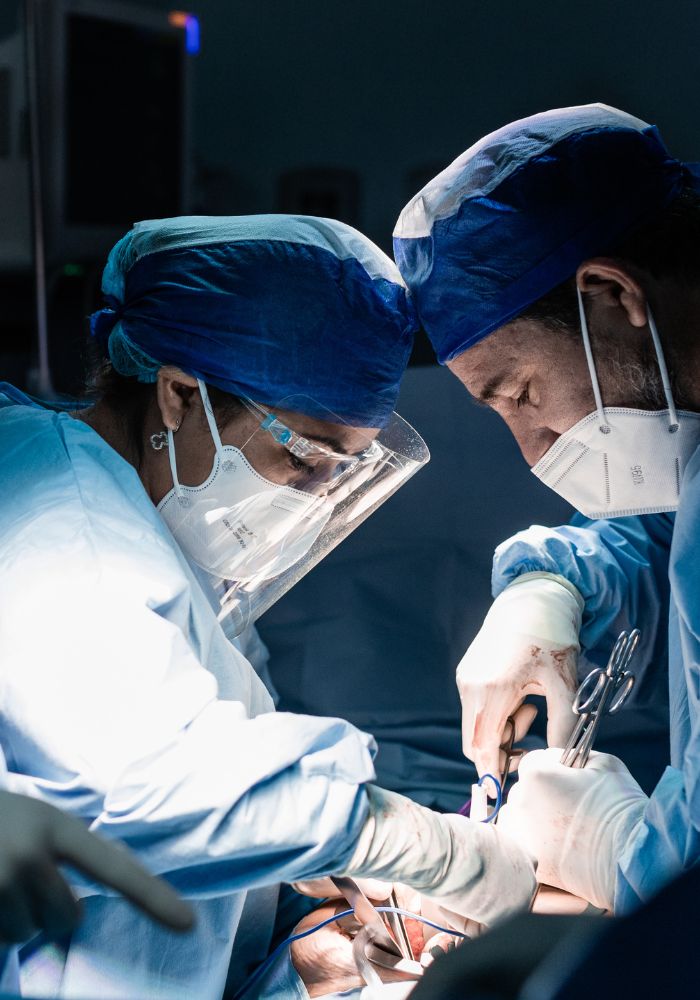 A man wearing a blue hat and a white mask is performing an operation.