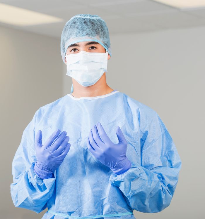A man wearing a blue gown and gloves.