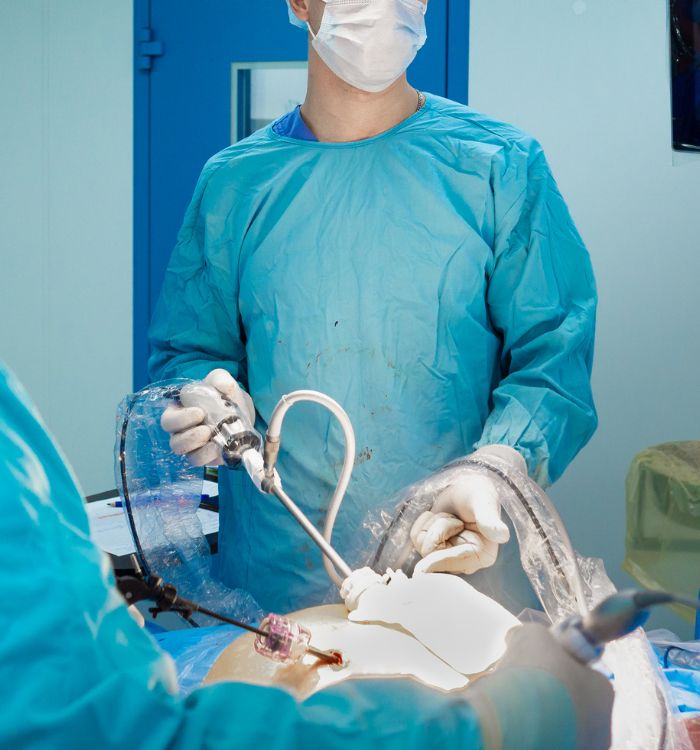 A man in a blue shirt and gloves is working on a patient.