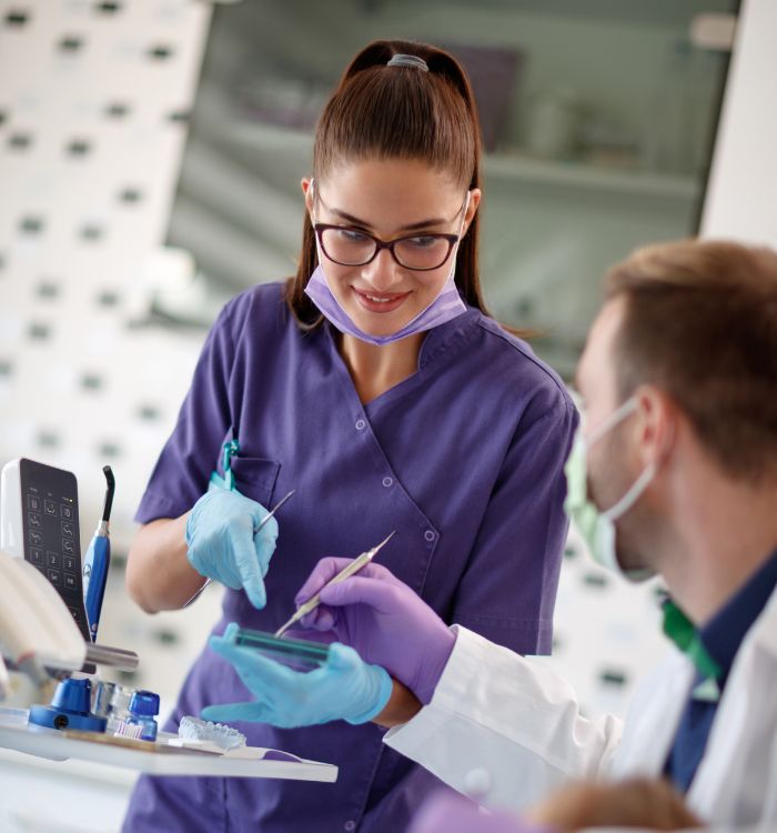 A woman in a purple shirt is holding something for the dentist.