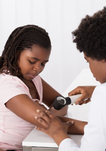 A woman is getting her skin checked by a nurse.