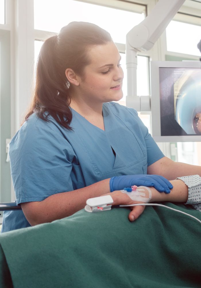 A woman in a blue shirt is attending to a patient.