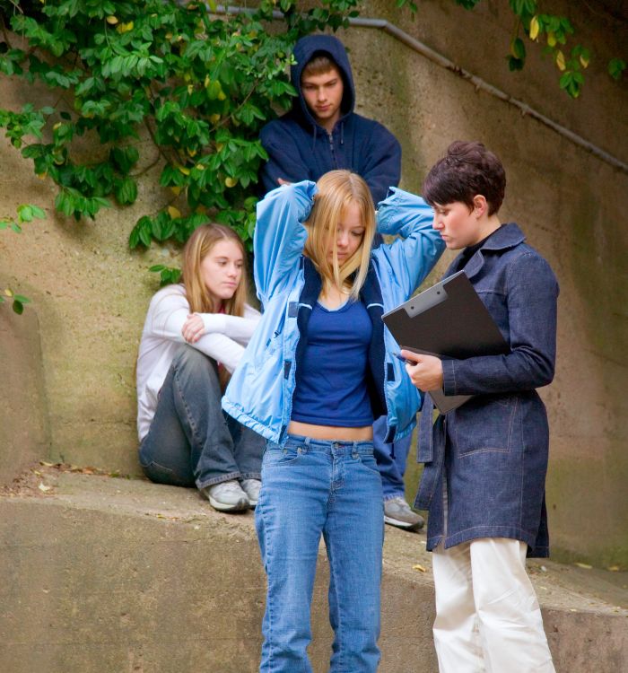 A woman in a blue jacket is talking to a girl in a blue shirt.