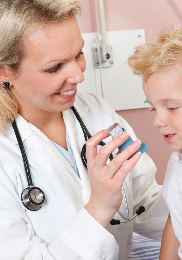 A woman in a white coat is showing a young boy how to use a device.
