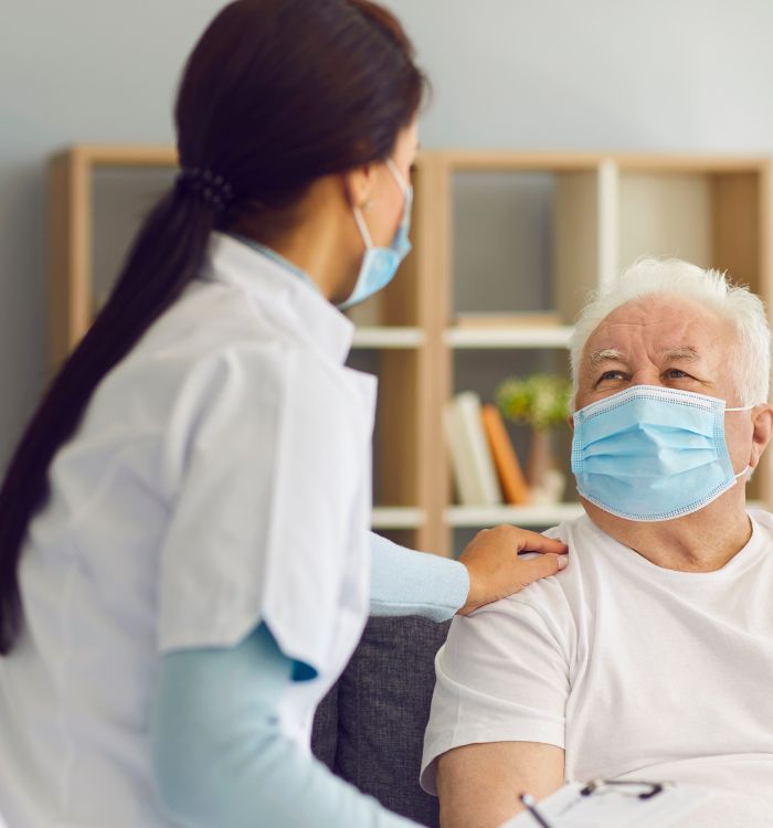 A woman wearing a white shirt and blue sleeves is talking to an older man.