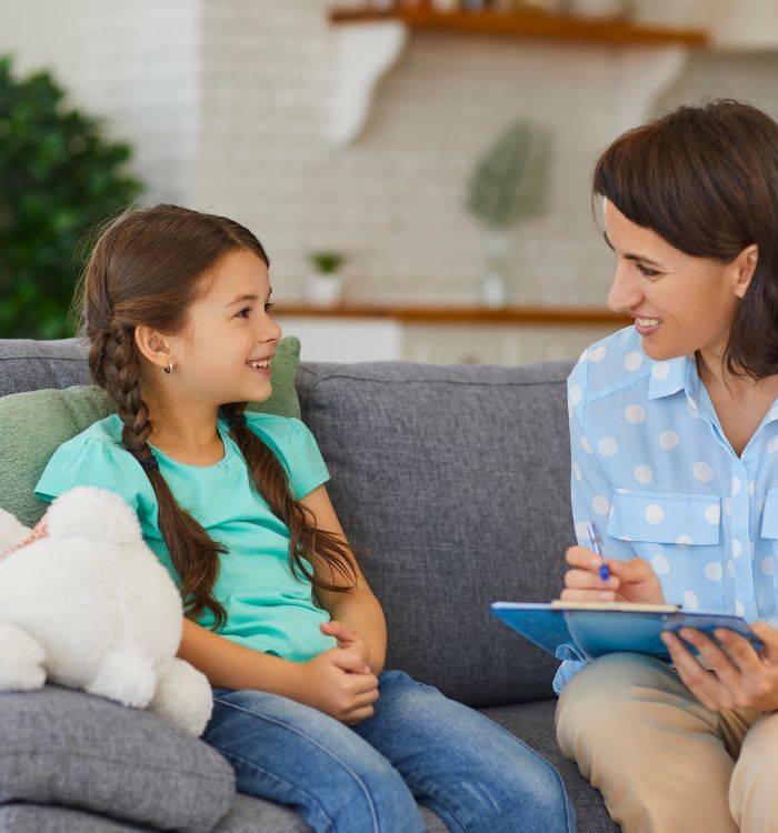 A woman sitting on a couch with a little girl.