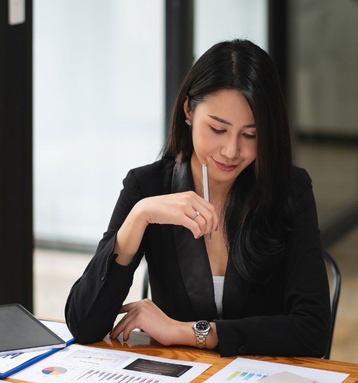 A woman in a black suit and white shirt is writing on a piece of paper.