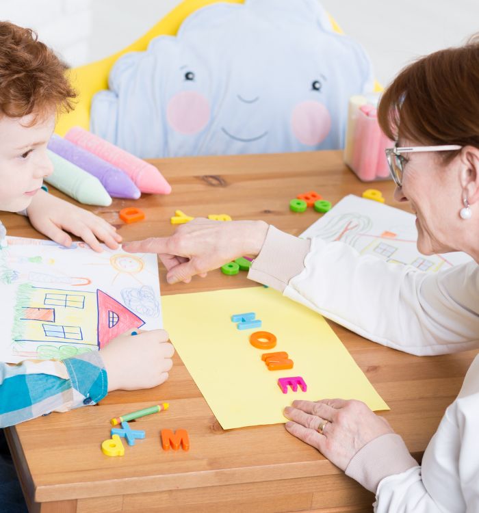 A woman and a boy are sitting at a table drawing.