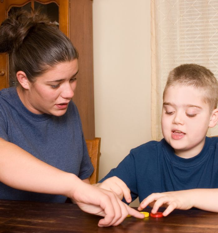 A woman and a boy play with a toy on a table.