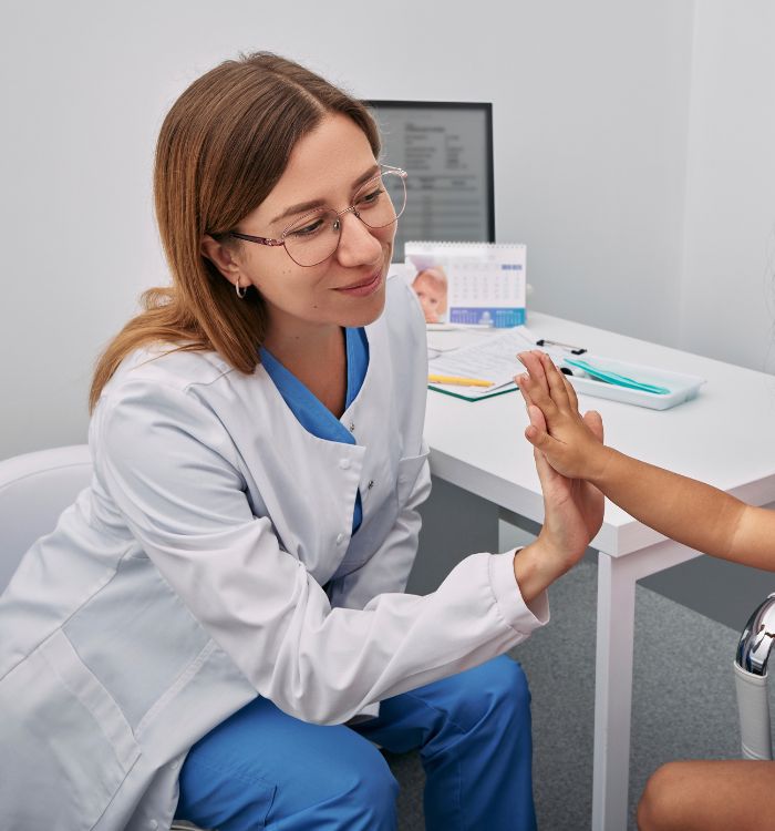 A woman in a white coat is helping a child.