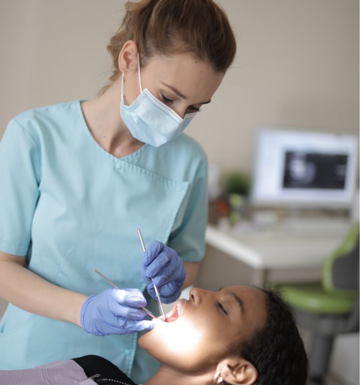 A woman in a blue shirt is holding a toothbrush and a pair of scissors.