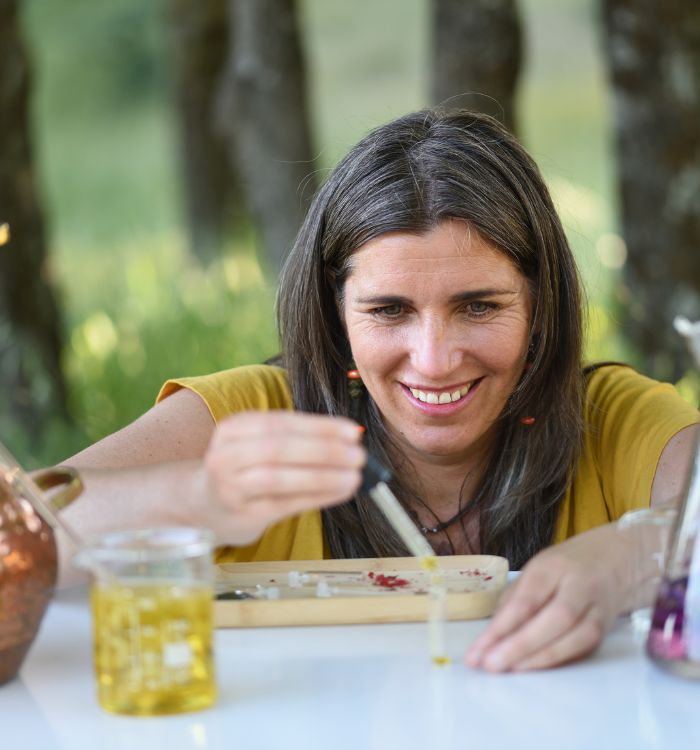 A woman with long hair and a yellow shirt is smiling and holding a glass.