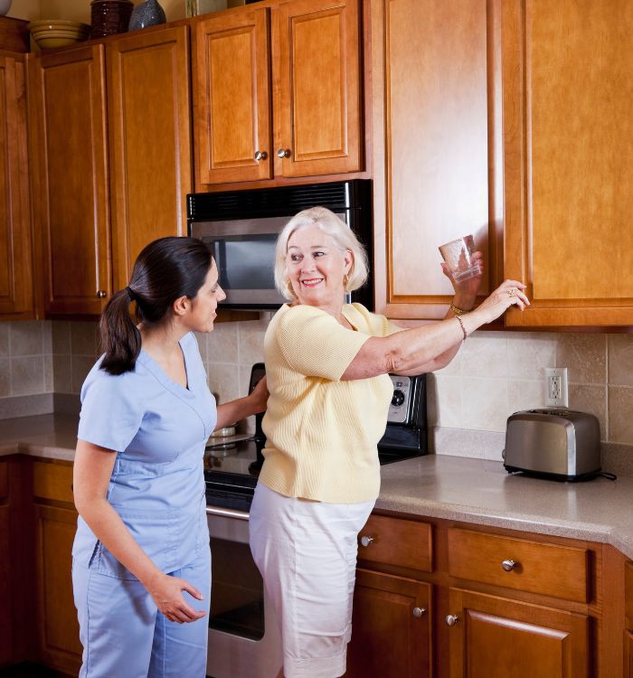 Two women in a kitchen with a microwave and a toaster.