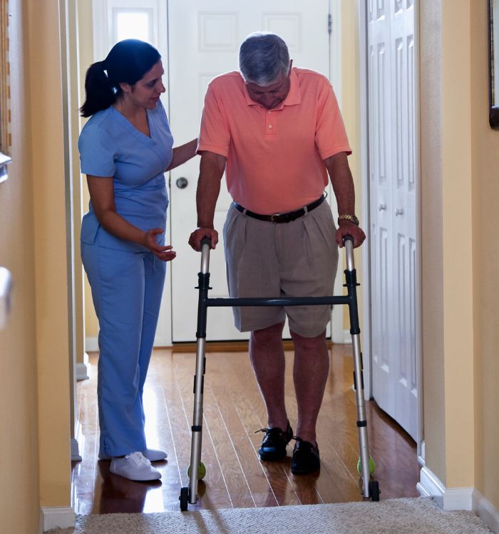 A woman in a blue dress helping an older man with a cane.