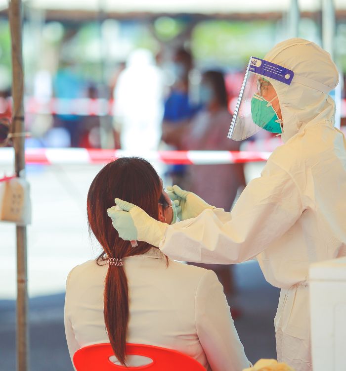 A woman getting test by a person wearing a white mask.